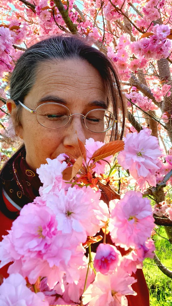 O'Shana J. Kosarev with closed eyes beside a blossoming cherry tree
