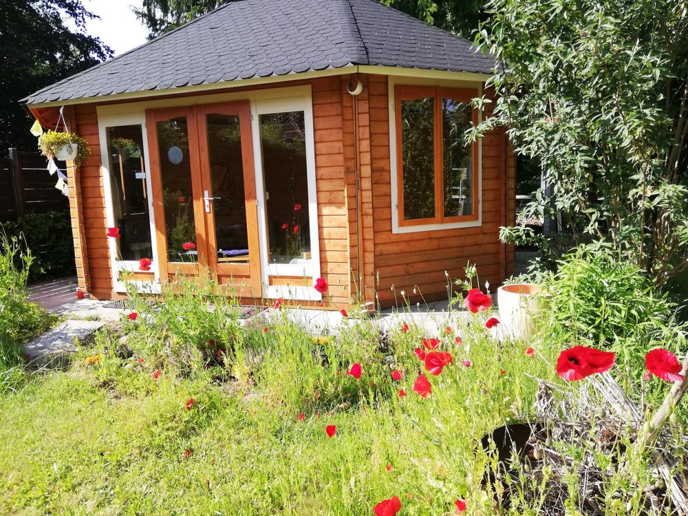 Wooden pavilion in a garden with red poppies in front